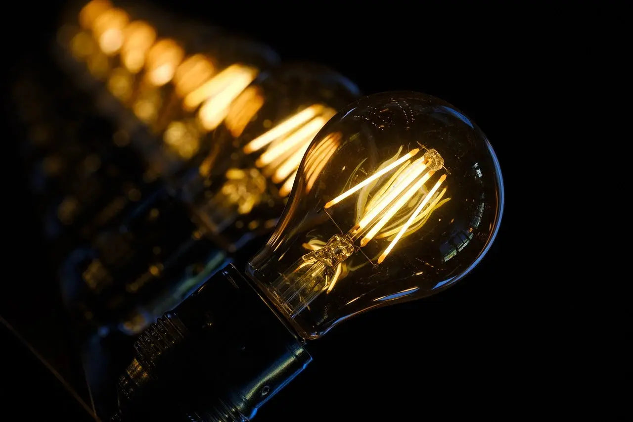 A row of illuminated light bulbs against a solid black background, creating a striking visual contrast.