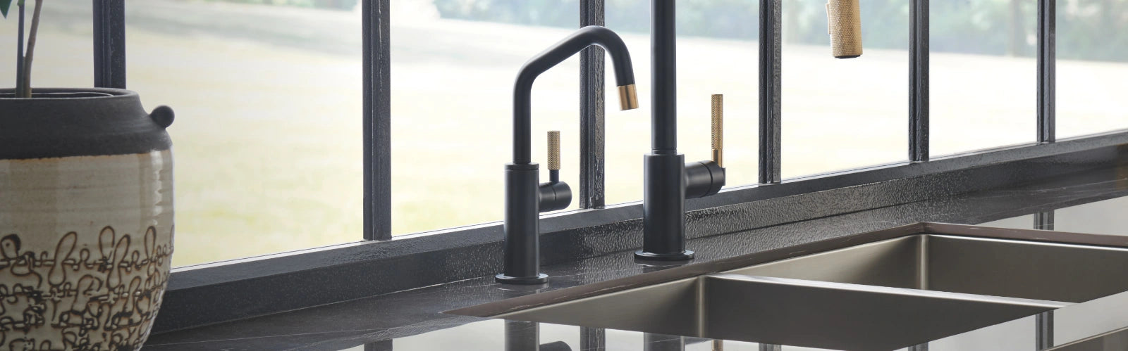 A kitchen sink featuring a black faucet and a window above, providing natural light and a modern aesthetic.