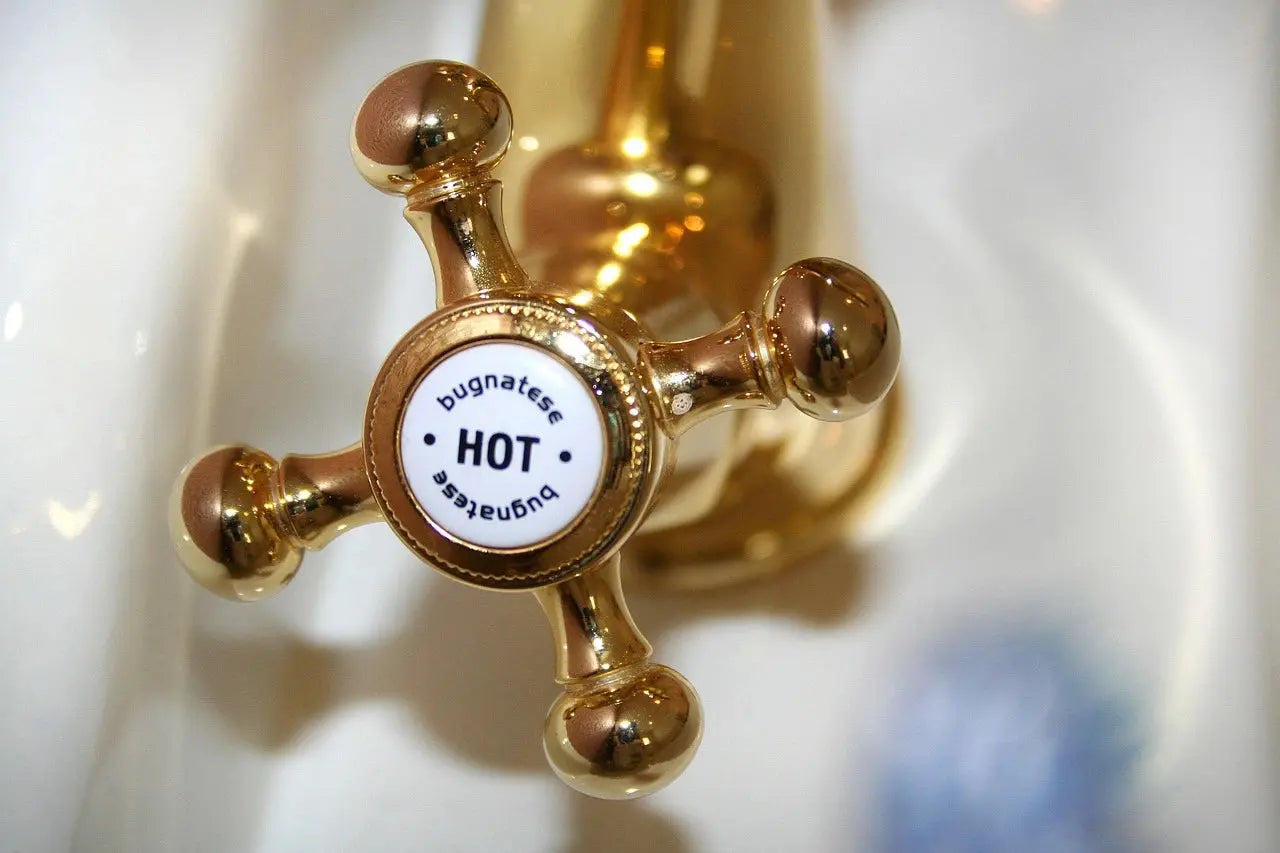 A close-up view of a gold faucet featuring a sign attached to it, highlighting its elegant design and functionality.