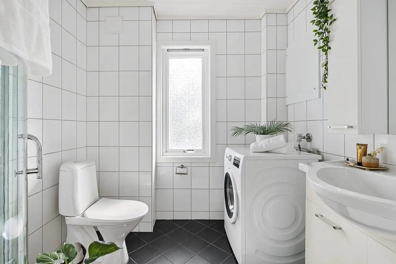 A bathroom featuring smart toilets, a washer and dryer, and a sink, designed for functionality and convenience.