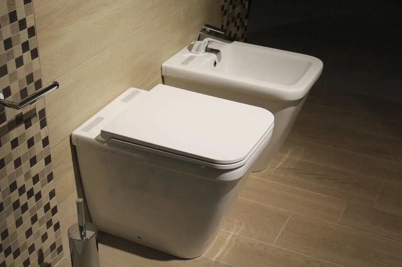 A clean bathroom featuring a reliable white toilet and a modern bidet against a neutral wall.